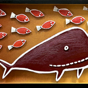 Grande baleine rouge en bois découpé entourée de petits poissons sur fond jaune