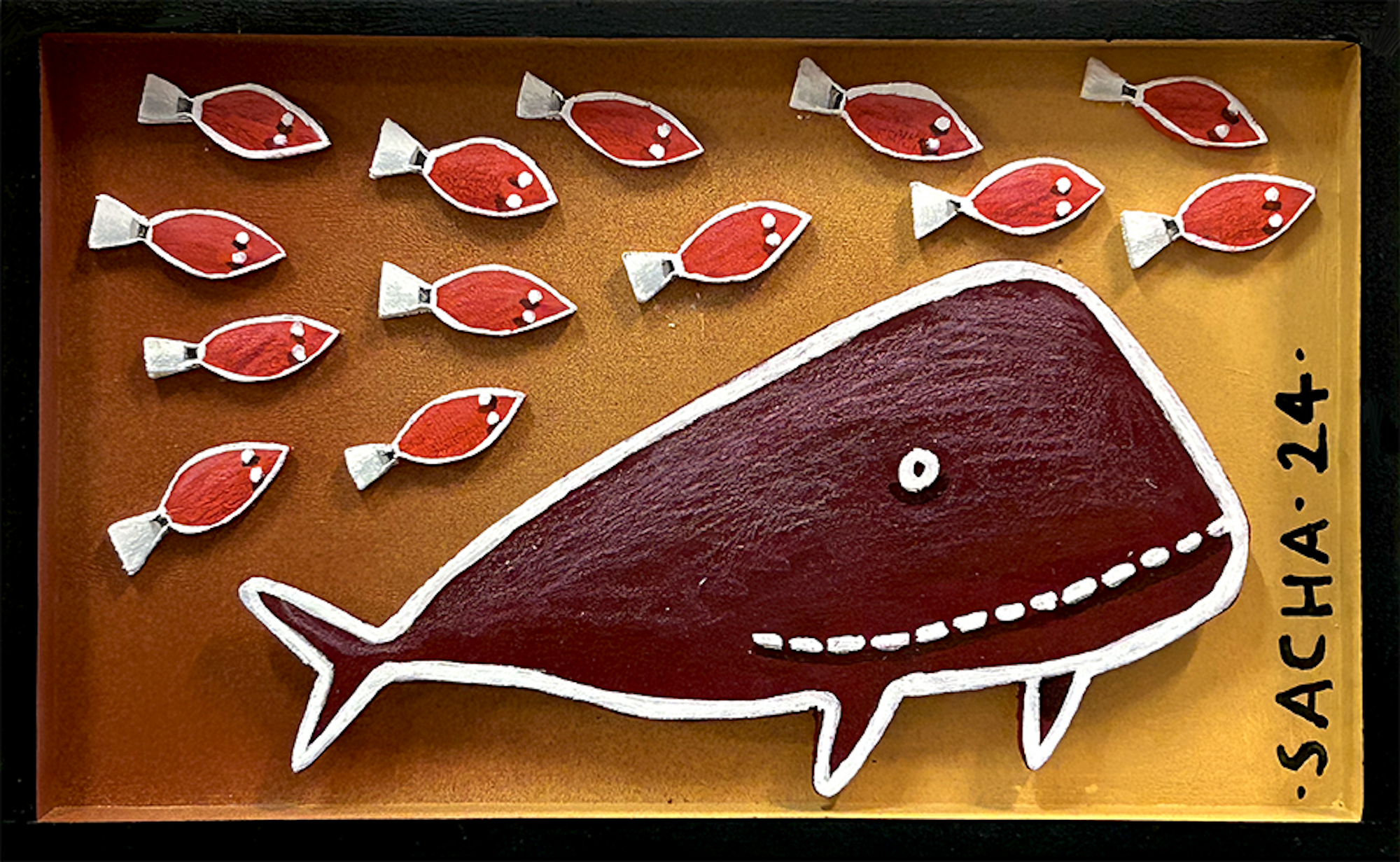 Grande baleine rouge en bois découpé entourée de petits poissons sur fond jaune