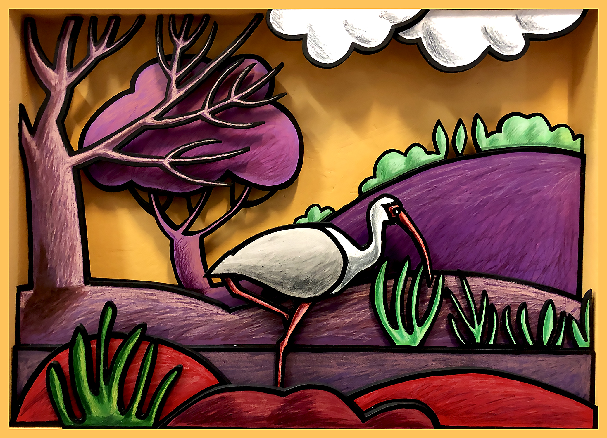 Diorama représentant une cigogne dans un paysage aux collines violettes et arbres stylisés, en acrylique sur bois avec découpes
