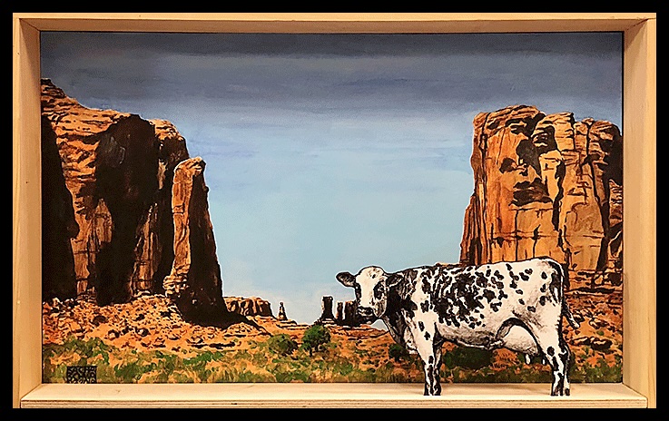Diorama représentant une vache devant un paysage rocheux désertique aux formations monumentales, en acrylique sur bois