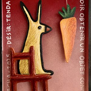 Lapin stylisé assis sur une chaise face à une carotte suspendue, en bois découpé sur fond rouge avec inscriptions, série Boîtes, 2025.